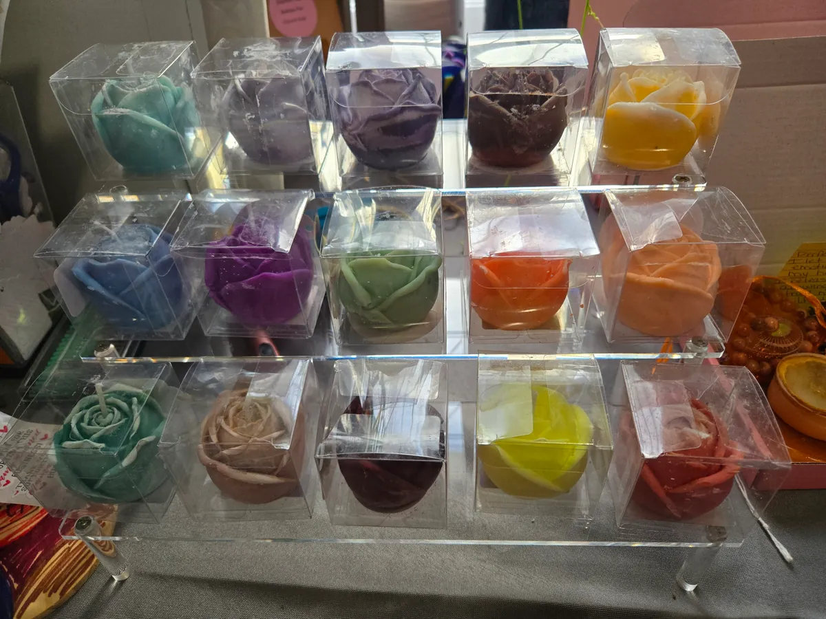 Display rack of rose-shaped candles in over a dozen colors